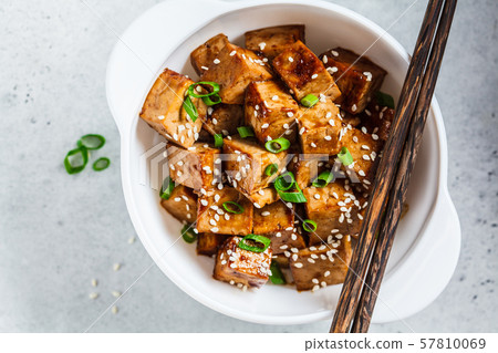 Fried tofu in teriyaki sauce in white bowl 57810069
