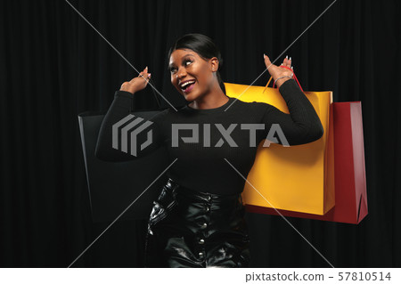 Young woman in dress shopping on black background 57810514