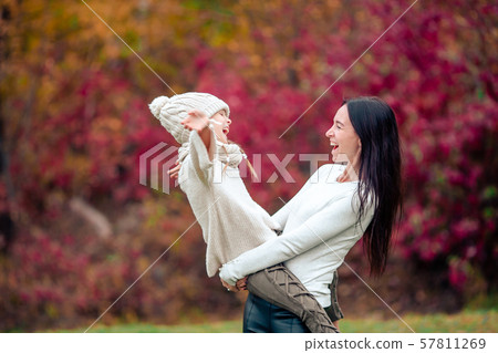 Little girl with mom outdoors in park at autumn day Little girl with mom outdoors in park at autumn day 57811269