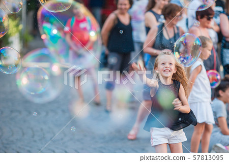 Adorable little girl blowing soap bubbles in Trastevere in Rome, Italy 57813095