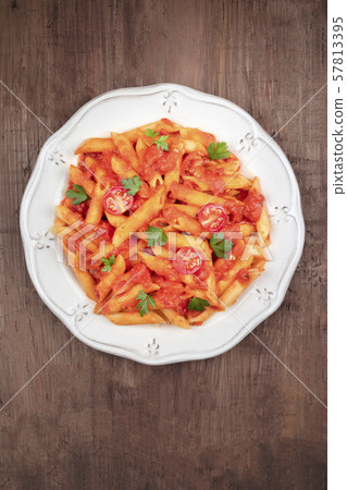 Penne pasta with tomato sauce and parsley, shot from above on a dark rustic wooden background with a 57813395