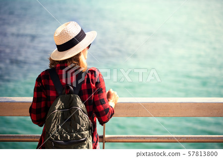A young woman with a backpack sits on the walk 57813800