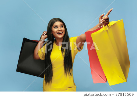 Young woman in dress shopping on blue background 57815509