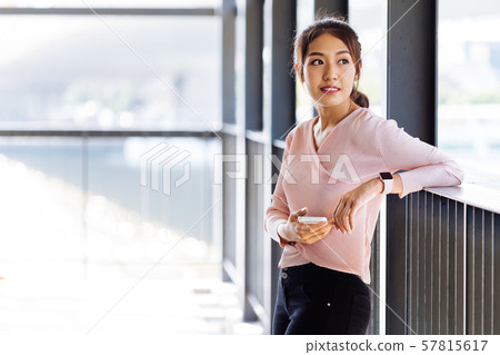 Asian woman leaning on handle and surfing smartphone 57815617