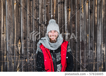 Young man standing against wooden background outdoors in winter. 57816005