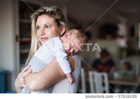 A beautiful young mother with a sleeping newborn baby at home. Copy space. A beautiful young mother with a sleeping newborn baby at home. Copy space. 57816289