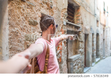 Girl following boyfriend holding hands in old european street laughing and smiling 57816349