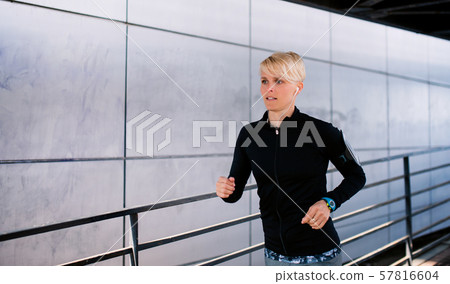 Young sportswoman doing exercise outdoors in city, running. 57816604