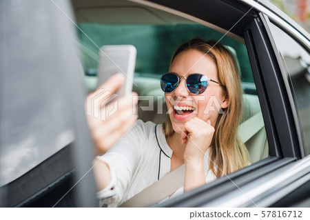 Business woman sitting on back seat in taxi car, taking selfie. Business woman sitting on back seat in taxi car, taking selfie. 57816712