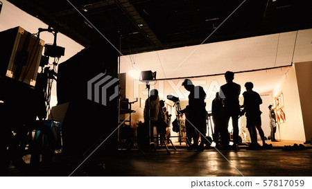 Behind the shooting video production and lighting set for filming which movie crew team working and silhouette shadow of camera and professional equipment in big studio for commercial advertising. 57817059