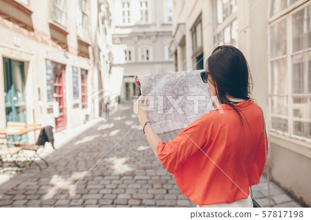 Young woman with a city map in city. Travel tourist girl with map in Vienna outdoors during holidays Young woman with a city map in city. Travel tourist girl with map in Vienna outdoors during holidays 57817198