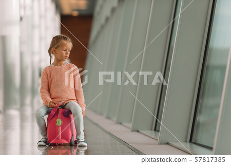 Adorable little girl in airport with her luggage waiting for boarding Adorable little girl in airport with her luggage waiting for boarding 57817385