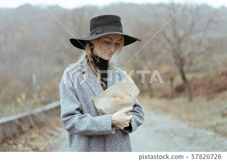 woman in a hat and coat stands in the rain outside woman in a hat and coat stands in the rain outside 57820726