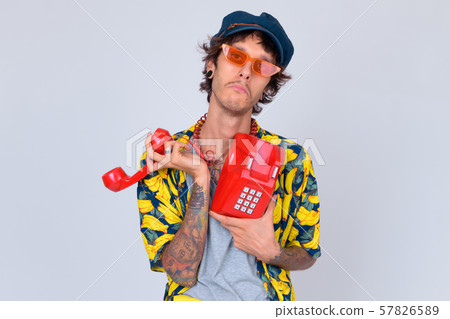 Portrait of young rebellious man looking sad while using old telephone Portrait of young rebellious man looking sad while using old telephone 57826589