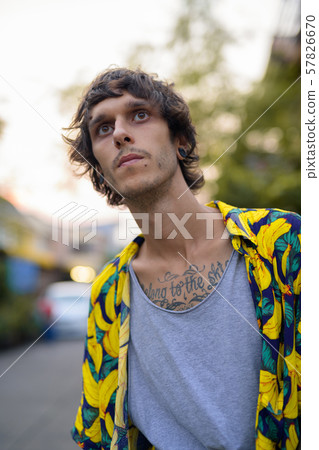 Portrait of young rebellious man thinking and waiting outdoors 57826670