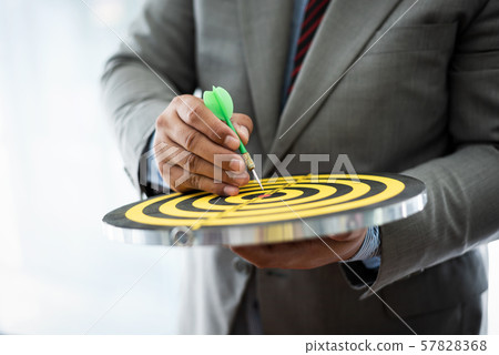 Business man poiting to center of dartboard for Business man poiting to center of dartboard for 57828368