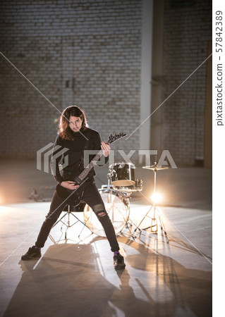 A musician man with long hair playing guitar - looking in the camera 57842389