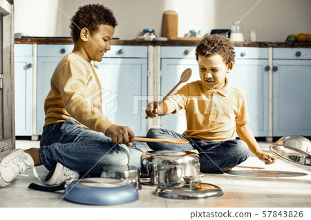 Children sitting on the kitchen floor and playing with creative resources. 57843826