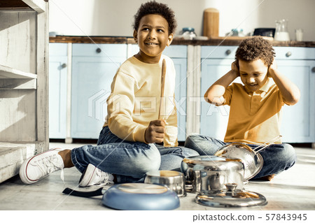 Boy covering ears while his brother trying to play on the dishes. 57843945