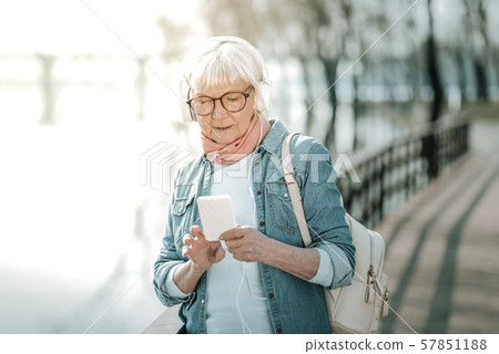 Focused vigorous dame in massive headsets holding a music player 57851188