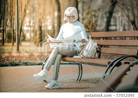 Serious superannuated madam wearing glasses and looking through paper 57852095