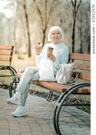 Cheerful beautiful aged dame tasting of coffee and cake 57852470