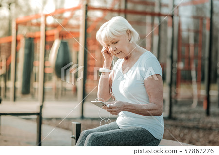 Retired lady in shape putting a headphone to the ear Retired lady in shape putting a headphone to the ear 57867276