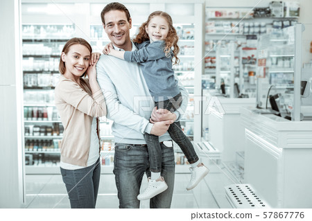 Joyful mother, father and daughter smiling in the chemists shop Joyful mother, father and daughter smiling in the chemists shop 57867776