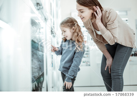 Girl pointing at medicine while mom brushing hair off ear. Girl pointing at medicine while mom brushing hair off ear. 57868339