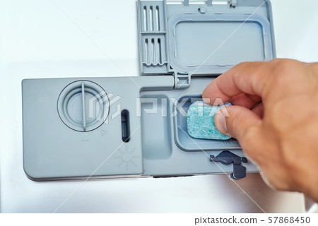 Hand putting soap tablet in dishwasher machine, close up. Kitchen domestic appliance concept Hand putting soap tablet in dishwasher machine, close up. Kitchen domestic appliance concept 57868450