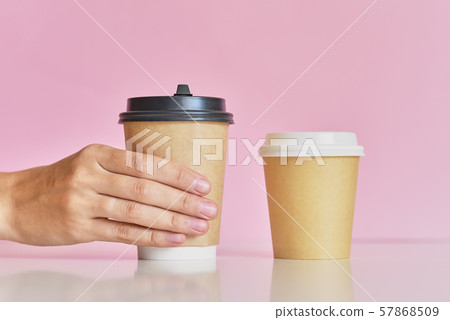 Woman hand take on of two coffee paper cup on a pink background 57868509