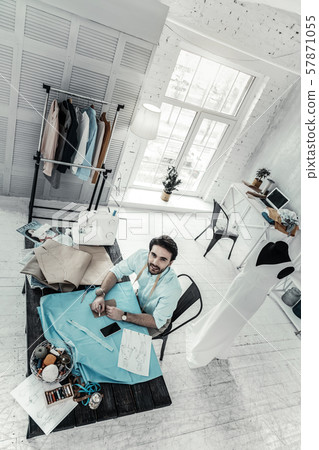 Handsome fashion designer sitting at his workplace Handsome fashion designer sitting at his workplace 57871055