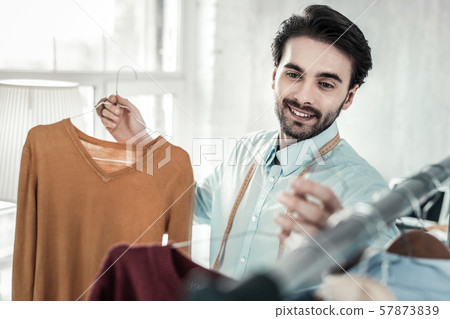 Handsome brunette tailor demonstrating his autumn collection Handsome brunette tailor demonstrating his autumn collection 57873839
