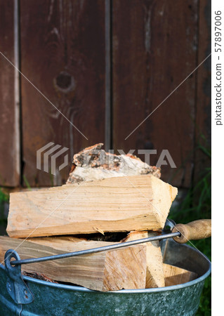 Bucketful of the firewood near a wood shed 57897006