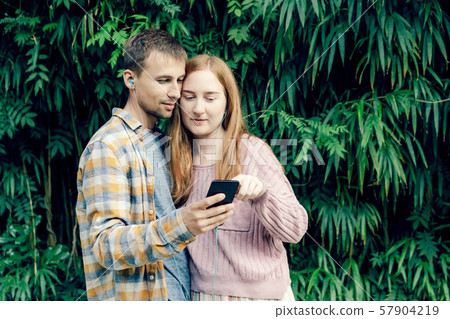 girl and guy in headphones look at the phone 57904219