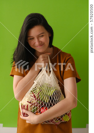 Young woman holds string bag mesh with vegetables 57920500
