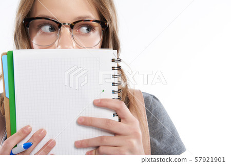 Cute teen girl holding pen and covering face with spiral notebook Cute teen girl holding pen and covering face with spiral notebook 57921901