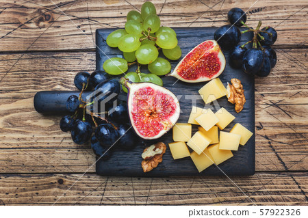 Cheese cubes, fresh fruit figs grapes Honey walnut on wooden chopping Board. Copy space. 57922326