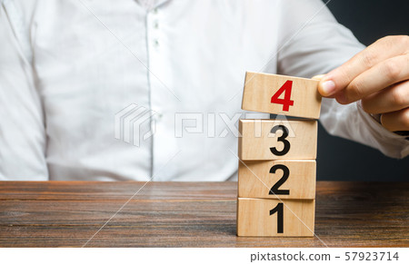A man puts numbered wooden blocks on top of each other. Alternate items and conditions for implementation. Contract road map. Organization and systematization, step by step instructions. A man puts numbered wooden blocks on top of each other. Alternate items and conditions for implementation. Contract road map. Organization and systematization, step by step instructions. 57923714