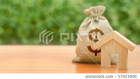 Wooden house figurine and money bag with a dollar symbol. Budget, subsidized funds. Mortgage loan for purchase housing, construction or modernization. Tax, building maintenance. Wooden house figurine and money bag with a dollar symbol. Budget, subsidized funds. Mortgage loan for purchase housing, construction or modernization. Tax, building maintenance. 57923800