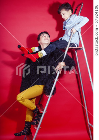 pretty young mother with little son on ladder on red background posing cheerful happy smiling pretty young mother with little son on ladder on red background posing cheerful happy smiling 57924106