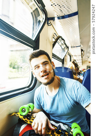 young pretty modern hipster guy traveller on train with skateboard alone, lifestyle vacation people 57924247