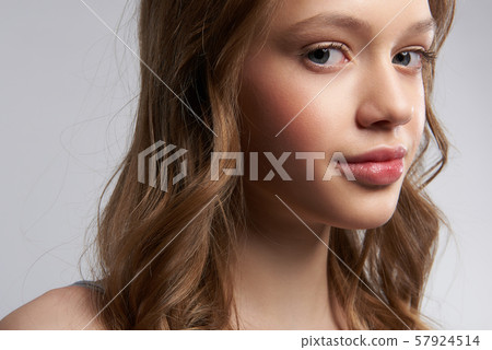 Charming teen girl with perfect skin standing against gray-white background 57924514