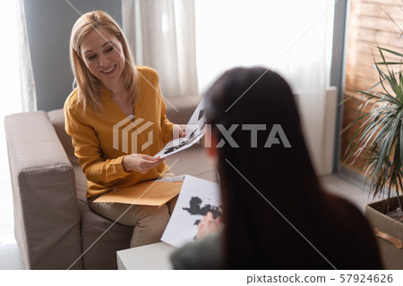 Smiling psychologist holding Ink blot test during seance with patient Smiling psychologist holding Ink blot test during seance with patient 57924626