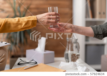 Psychologist is giving glass with water to her patient over the table 57924634