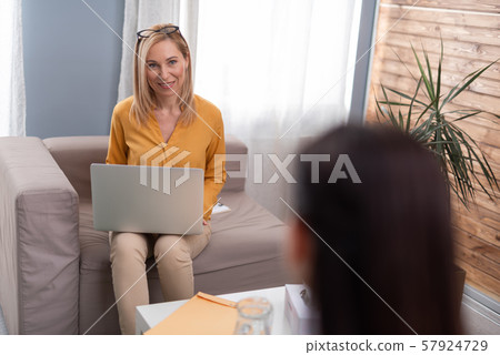 Psychologist talking to brunette female patient in consulting room 57924729