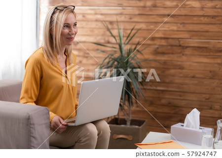 Beautiful psychologist holding laptop on knees in private consulting room 57924747
