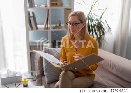 Beautiful psychologist holding test results in arms in private consulting room Beautiful psychologist holding test results in arms in private consulting room 57924861