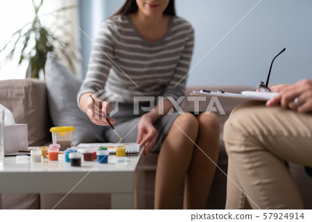 Patient painting picture while sitting at table indoors Patient painting picture while sitting at table indoors 57924914