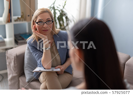 Psychologist with clipboard looking attentively at patient Psychologist with clipboard looking attentively at patient 57925077